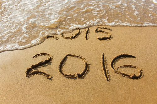 2015 and 2016 year written on sandy beach sea. Wave washes away 2015. The concept of 2015 is gone, come the new year 2016.